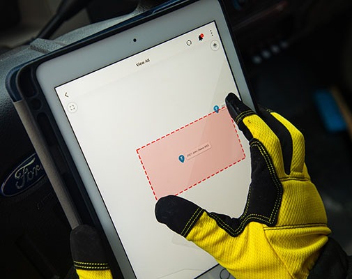 Heavy equipment driver setting a virtual perimeter around a location inside GPS fleet tracking software on a iPad.